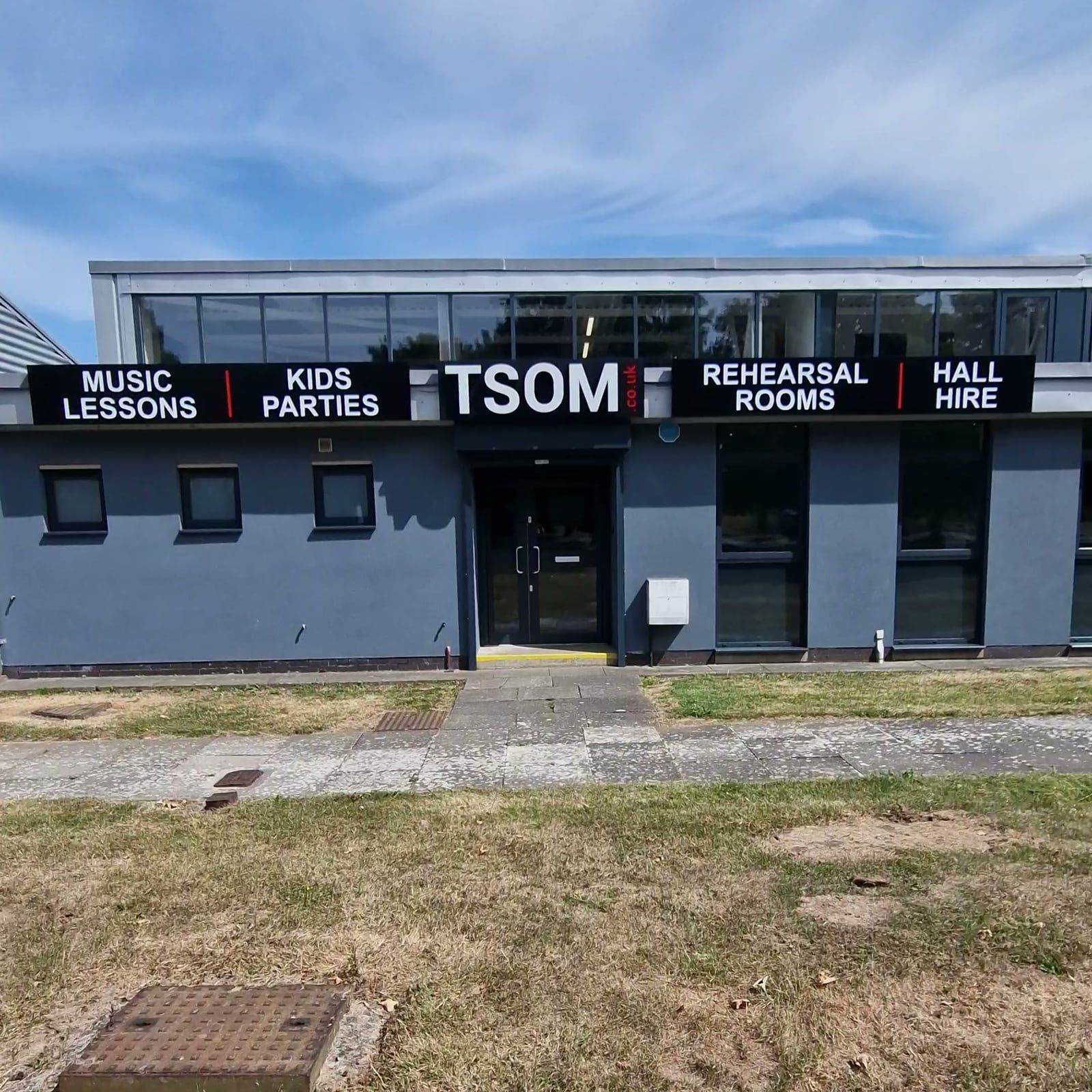 The front of Teesside School of Music on Dukes Way, with the TSOM, Kids Parties and Rehearsal Rooms signs above the entrance