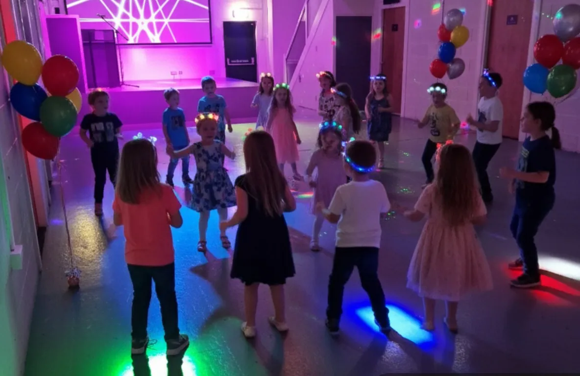 Children dancing at a disco party in the hall under coloured lights