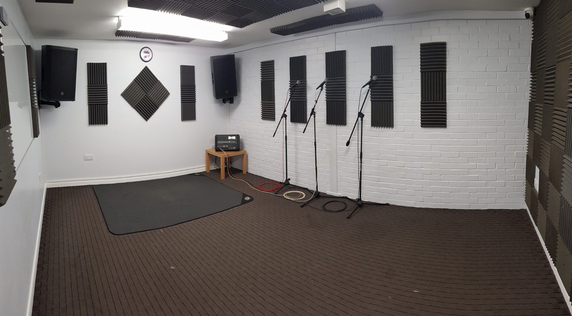 One of the two acoustically treated rehearsal rooms, with PA speakers, three mic stands and a drum mat