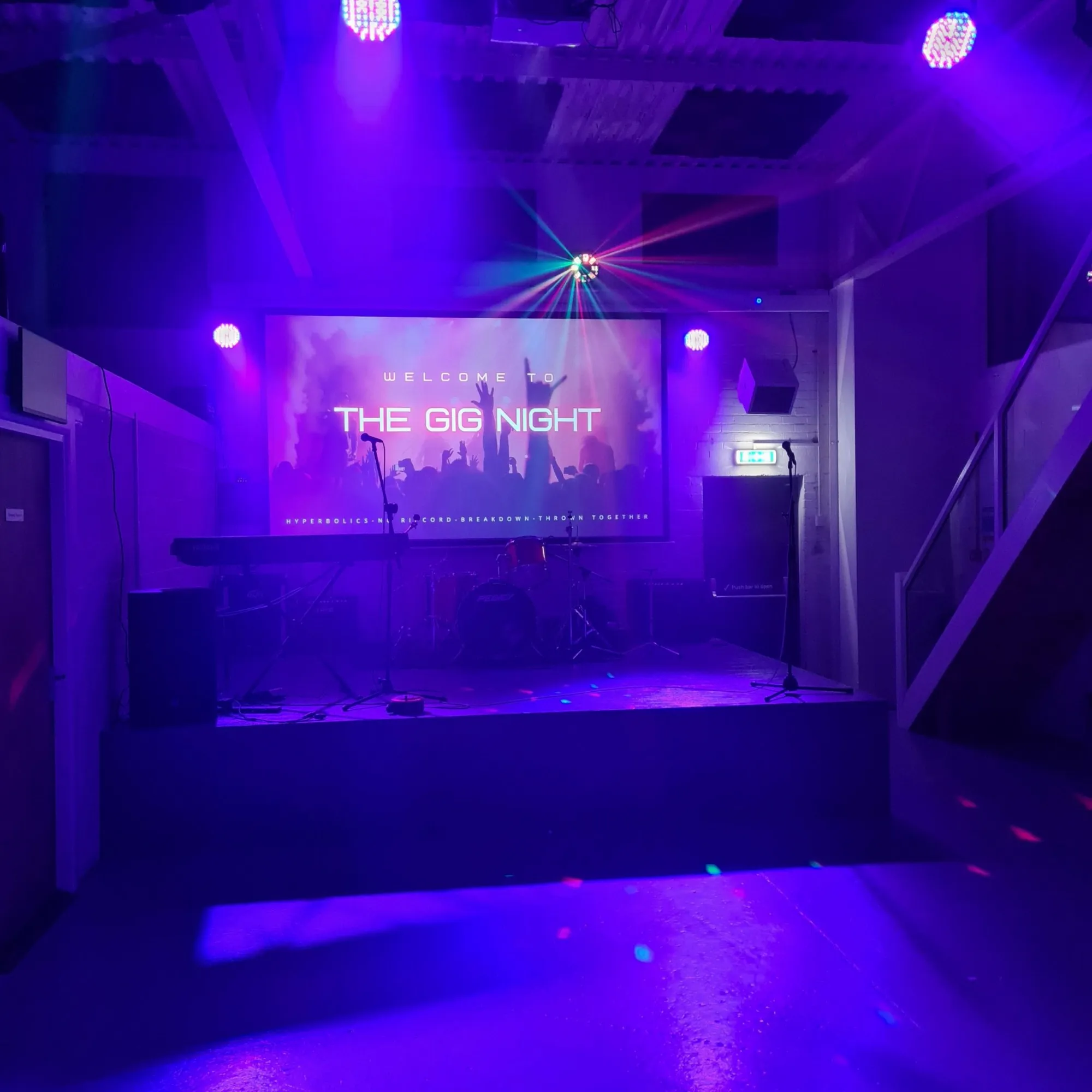The hall stage lit in purple with the big projector screen above it